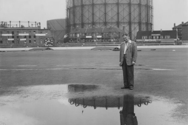 Head groundsman Bert Lock and the landmark gasometer are reflected in a pool of water on the wicket of the cricket pitch as bad weather and rain postpones the second day of the fourth Test match of the series between England and Pakistan on 13 August 1954 at the Kennington Oval cricket ground in London, United Kingdom.  (Photo by Dennis Oulds/Central Press/Hulton Archive/Getty Images).